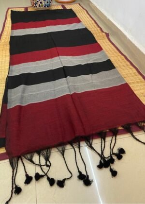 Black and red striped cotton saree with tassel details displayed on a woven mat.