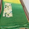 Green and yellow ombre saree paired with a floral blouse, displayed on a woven mat.